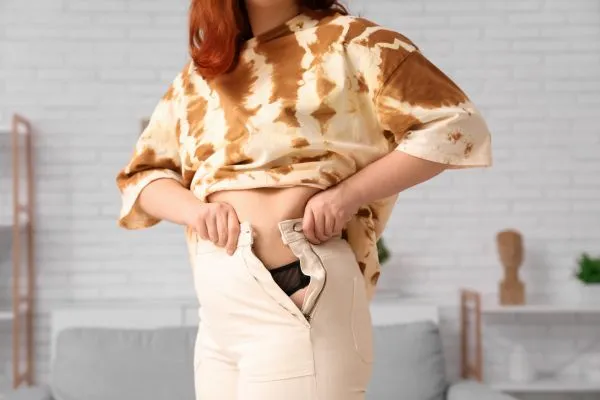 Image of woman trying to do her trousers up after pregnancy weight gain Wigan